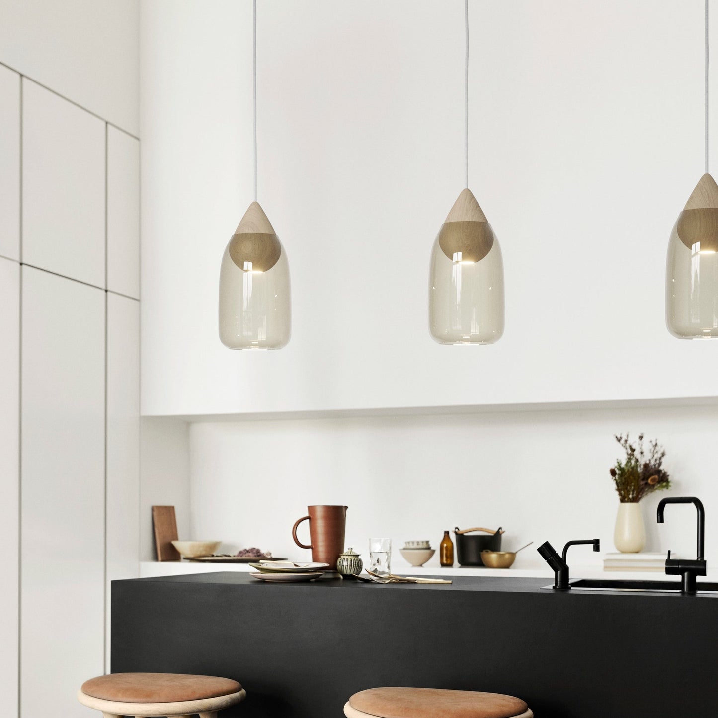 Modern kitchen with black island, wooden stools, and pendant lights.