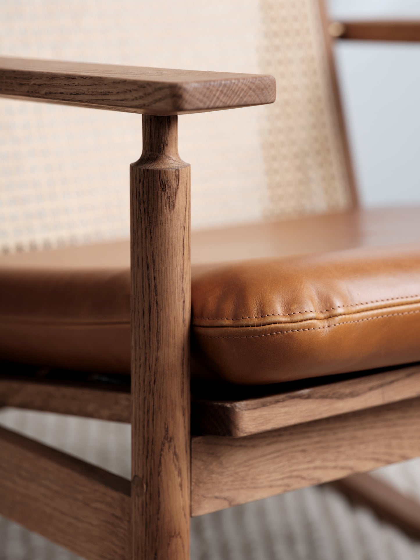 Close-up of a wooden chair with brown leather seat and backrest.
