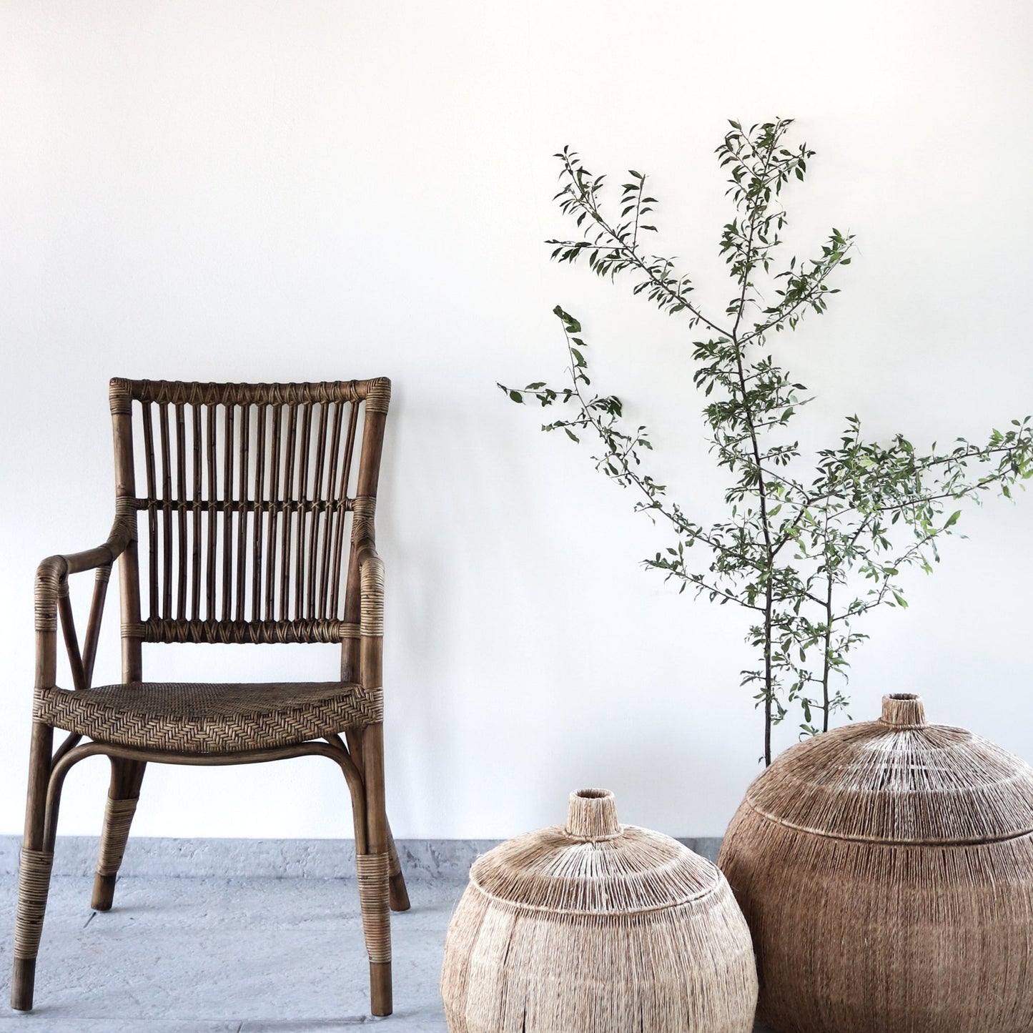 Wicker chair and decorative pots with a plant on a white floor and wall