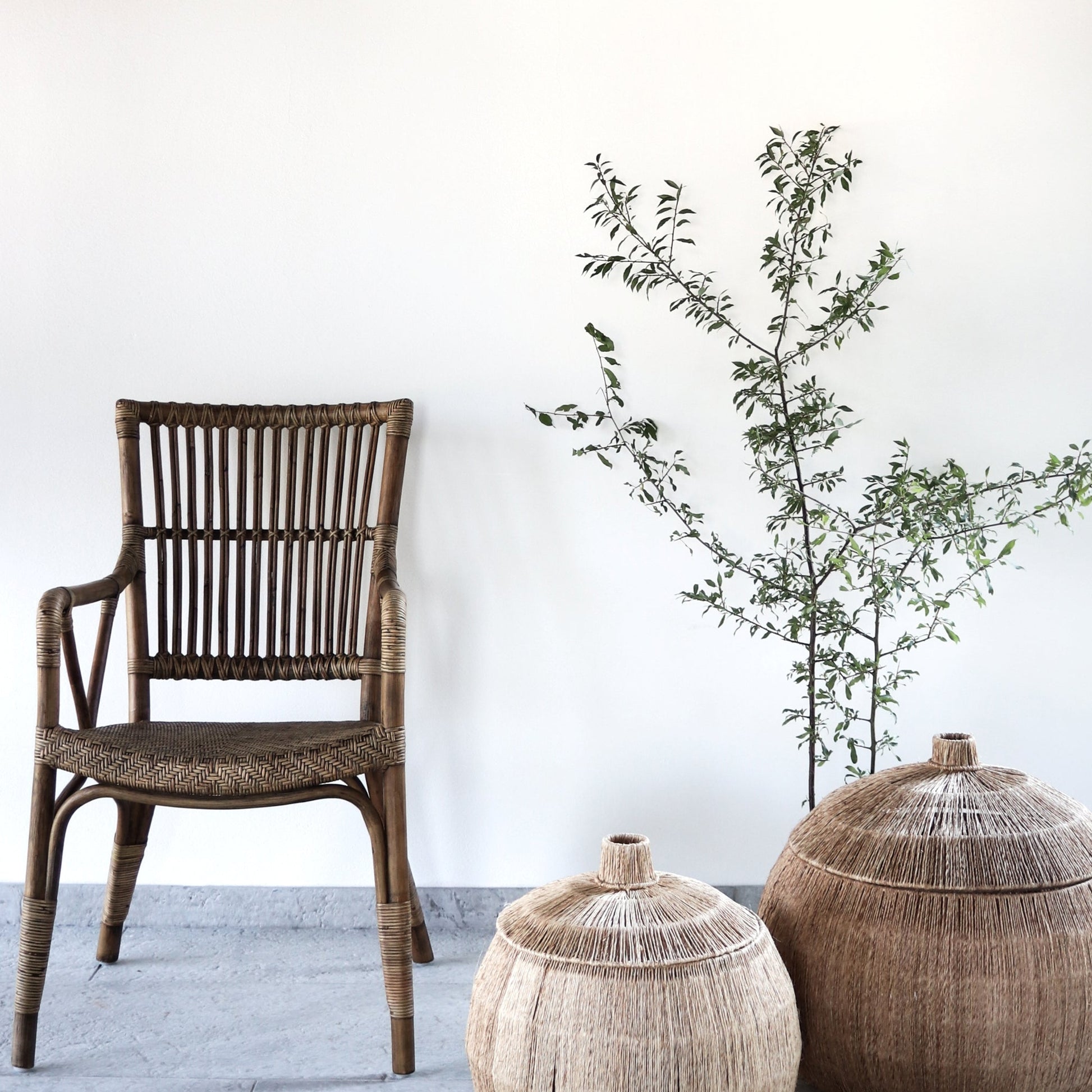 Wicker chair and decorative pots with a plant on a white floor and wall