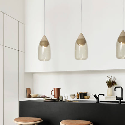 Modern kitchen with black island, wooden stools, and pendant lights.