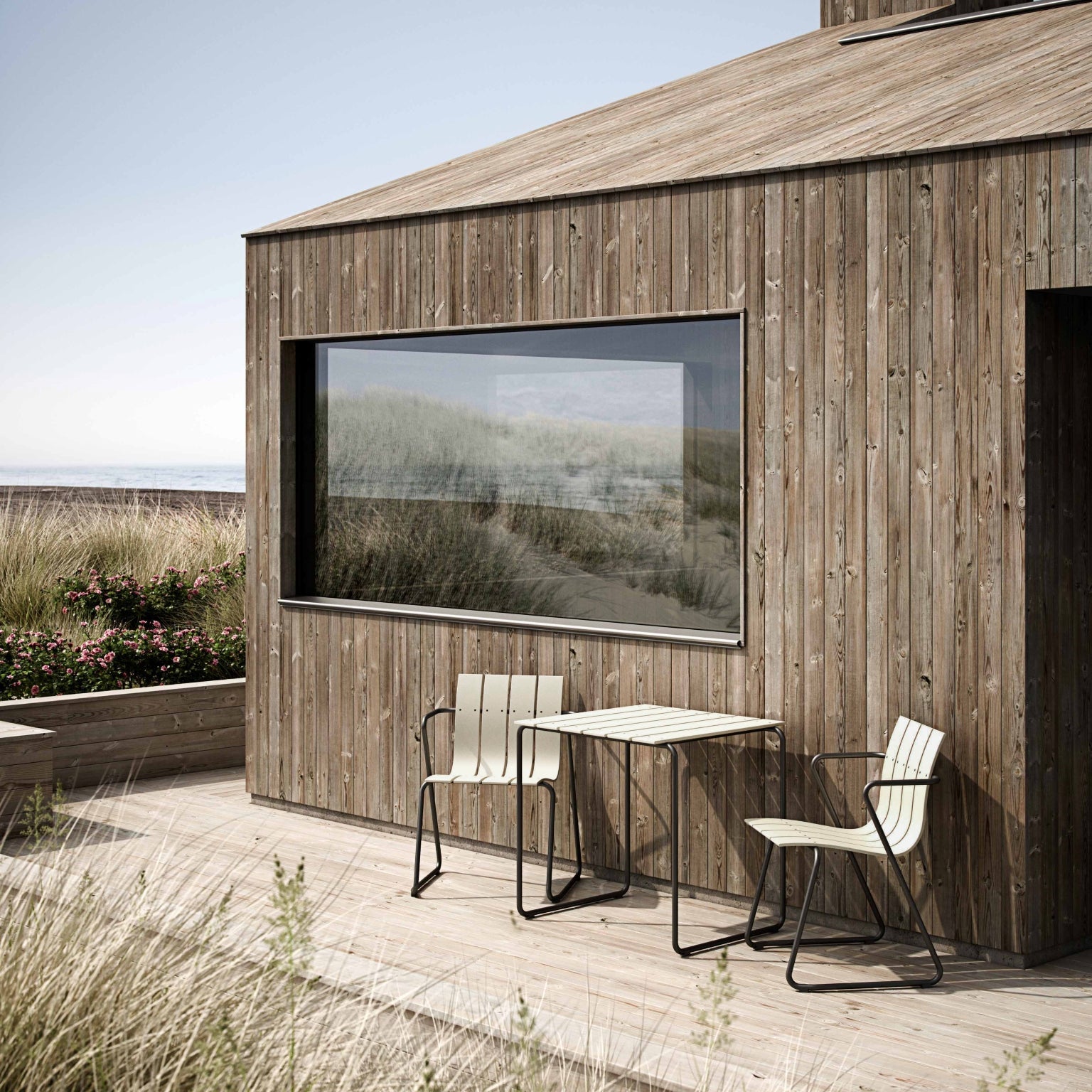 Wooden cabin with outdoor furniture on a deck, surrounded by natural scenery.