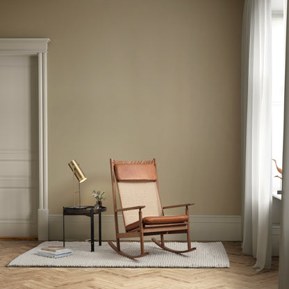 Rustic rocking chair in a room with beige walls and wooden flooring.